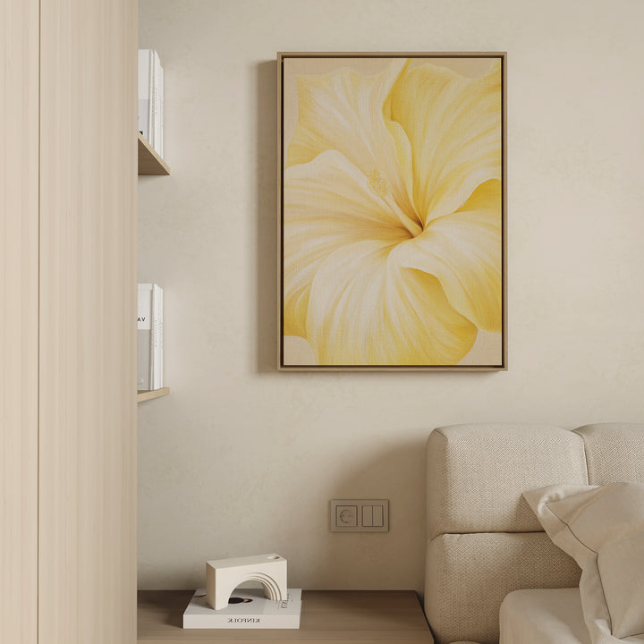 Golden Radiance Canvas Art, a framed painting depicting a large yellow flower, hangs as minimalist wall art above a light-colored couch, with books and a small white decor piece placed on nearby shelves.