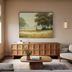 A cozy living room features a wooden sideboard, coffee table, sofa, and the Golden Rest Canvas Art—a wall-mounted print of a deer in a sunlit meadow. Soft natural light filters through the window, enhancing the serene atmosphere.