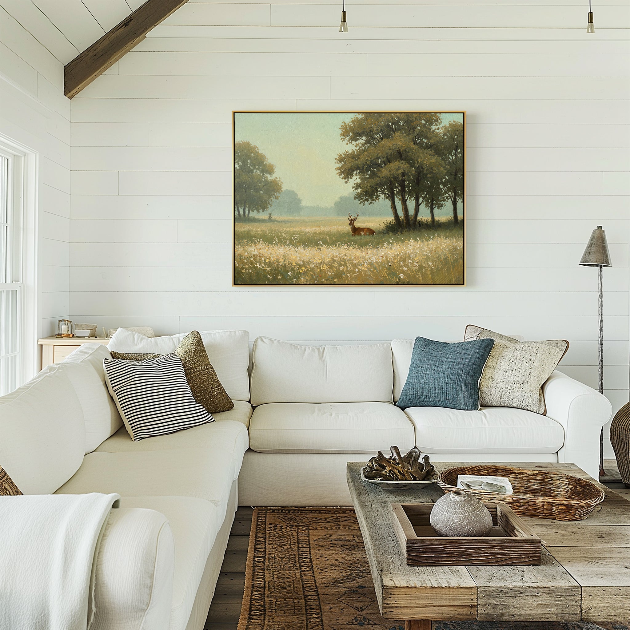A cozy living room with a white sectional, assorted pillows, a rustic wooden coffee table, and the Golden Rest Canvas Art of trees and a deer above the sofa—perfect for fans of inviting, comfortable interiors.