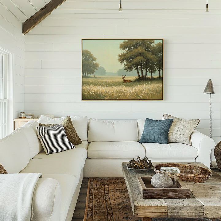 A cozy living room with a white sectional, assorted pillows, a rustic wooden coffee table, and the Golden Rest Canvas Art of trees and a deer above the sofa—perfect for fans of inviting, comfortable interiors.