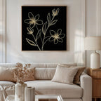 A neutral-toned living room with a white sofa, beige pillows, a wooden side table and lamp, dried flowers in a vase, and modern Golden Stems Canvas Art featuring minimalist floral line drawings on the wall.
