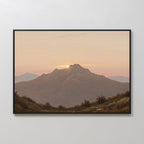 Golden Summit Canvas Art features a mountain at sunset with the sun behind the peak and a pastel sky. Shrubs and rolling hills complete this framed wall art, perfect for living room or bedroom decor.