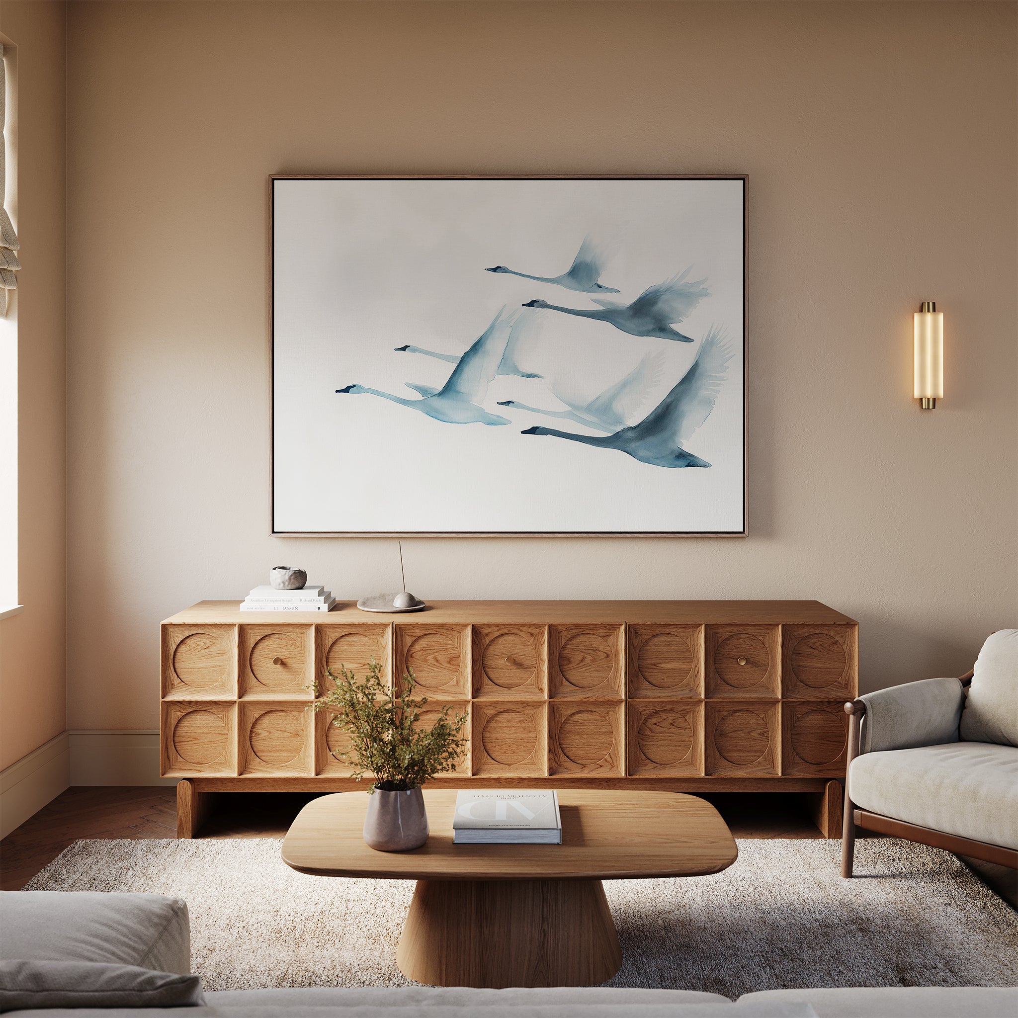 A cozy living room with a wooden coffee table and sideboard, neutral rug, and vase of flowers is enhanced by the Graceful Flock Canvas Art above the sideboard, adding modern Nordic nature decor with flying birds to the space.