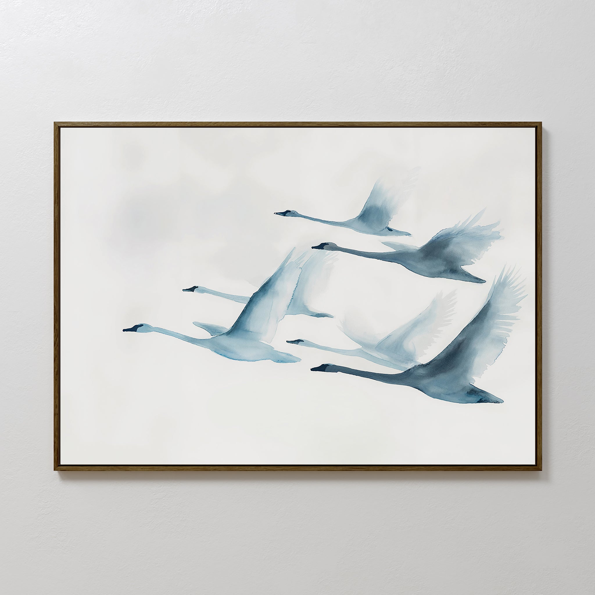 The Graceful Flock Canvas Art showcases six swans in flight, illustrated in soft blue watercolor on a white background, and is framed and displayed on a simple light-colored wall.