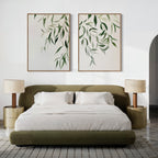 Modern bedroom featuring an olive green upholstered bed, white bedding, two beige nightstands with matching lamps, and the Graceful Leaves Set of 2 wall art above the headboard. A neutral palette and minimalist decor create a serene atmosphere.