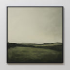 The Hills at Dusk Canvas Art features a framed minimalist misty landscape of rolling green hills, distant mountains, and an overcast sky in soft tones—an elegant wall art print for your living room decor.
