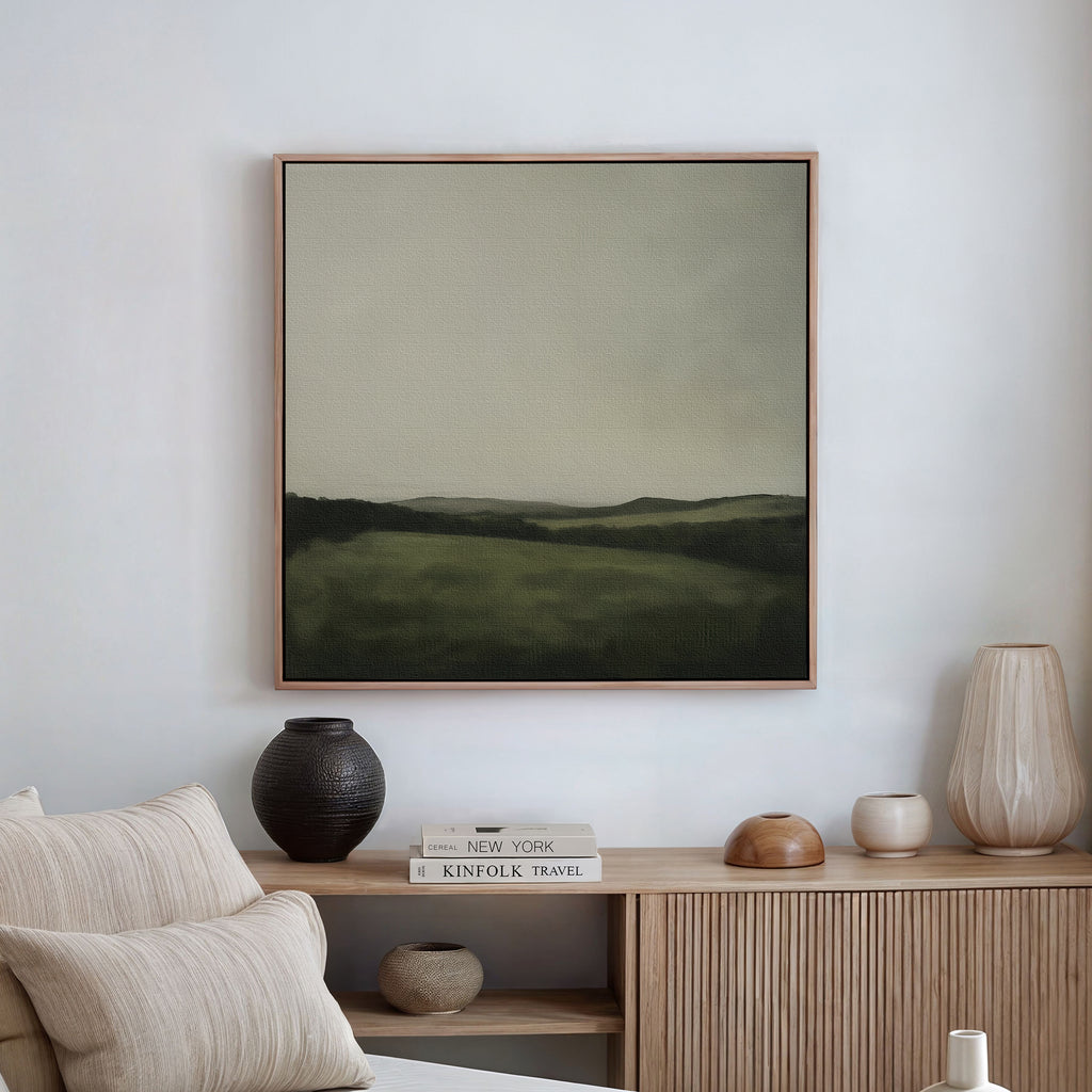 A minimalist living room features the Hills at Dusk Canvas Art above a wooden sideboard with books, vases, and decor. Soft, neutral tones create an elegant atmosphere that highlights this refined living room piece.