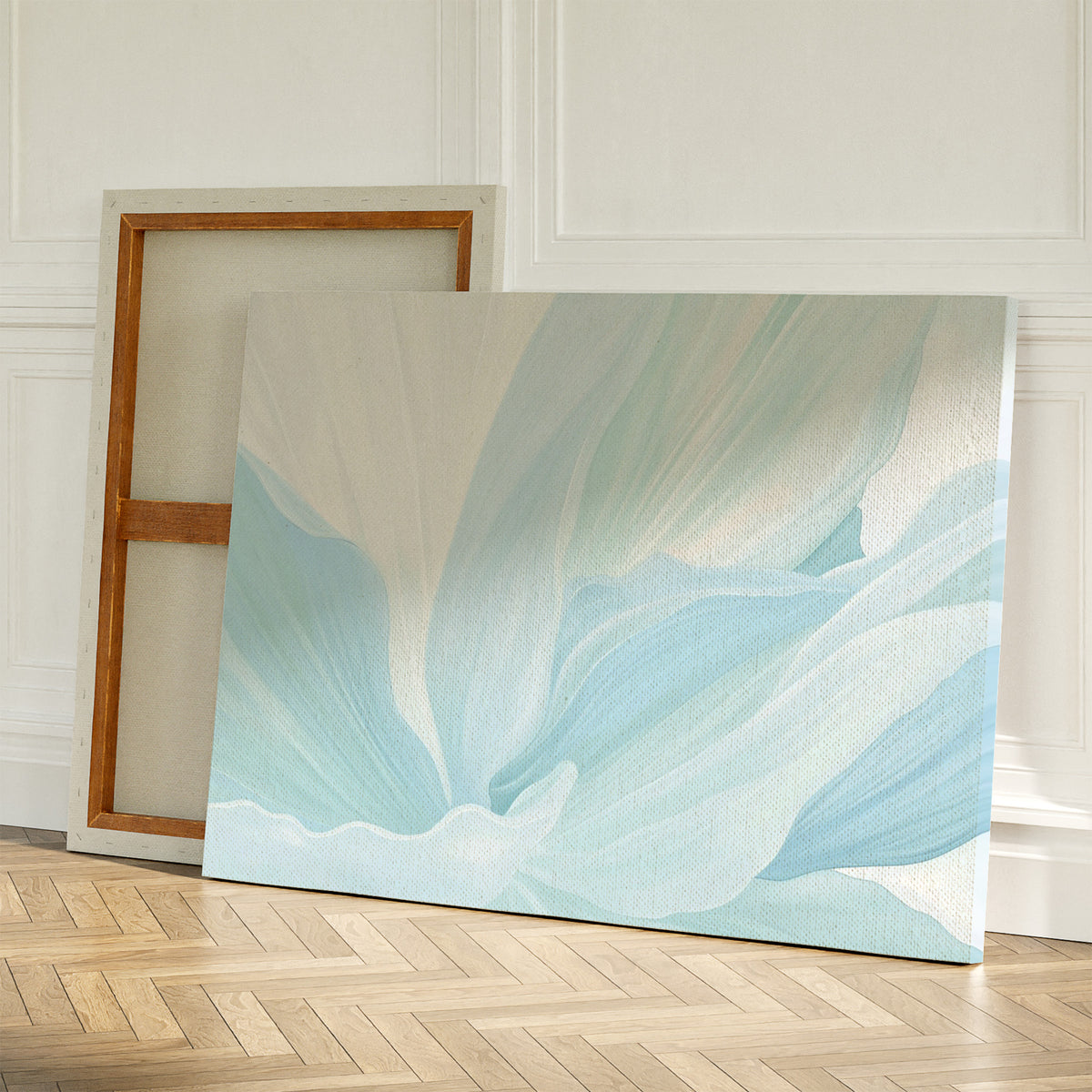 Two large canvases rest on a wooden floor against a white wall; one shows the back, while the other displays Icy Petals Abstract Canvas Art—a soft blue and white floral piece perfect as minimalist decor for a serene bedroom.