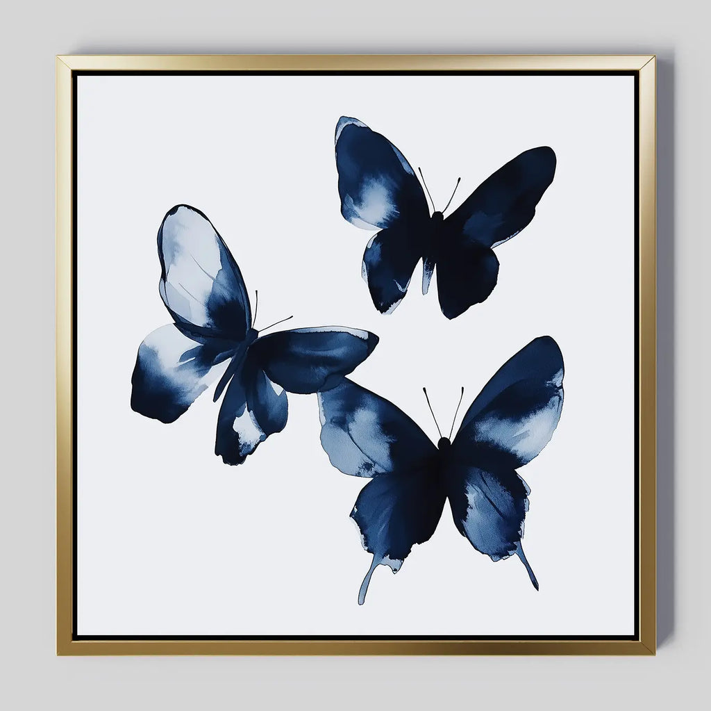 Indigo Flutter Canvas Art: a framed print with three blue abstract butterflies on a white background, finished with a gold metallic frame—ideal for adding modern decor style to your home.