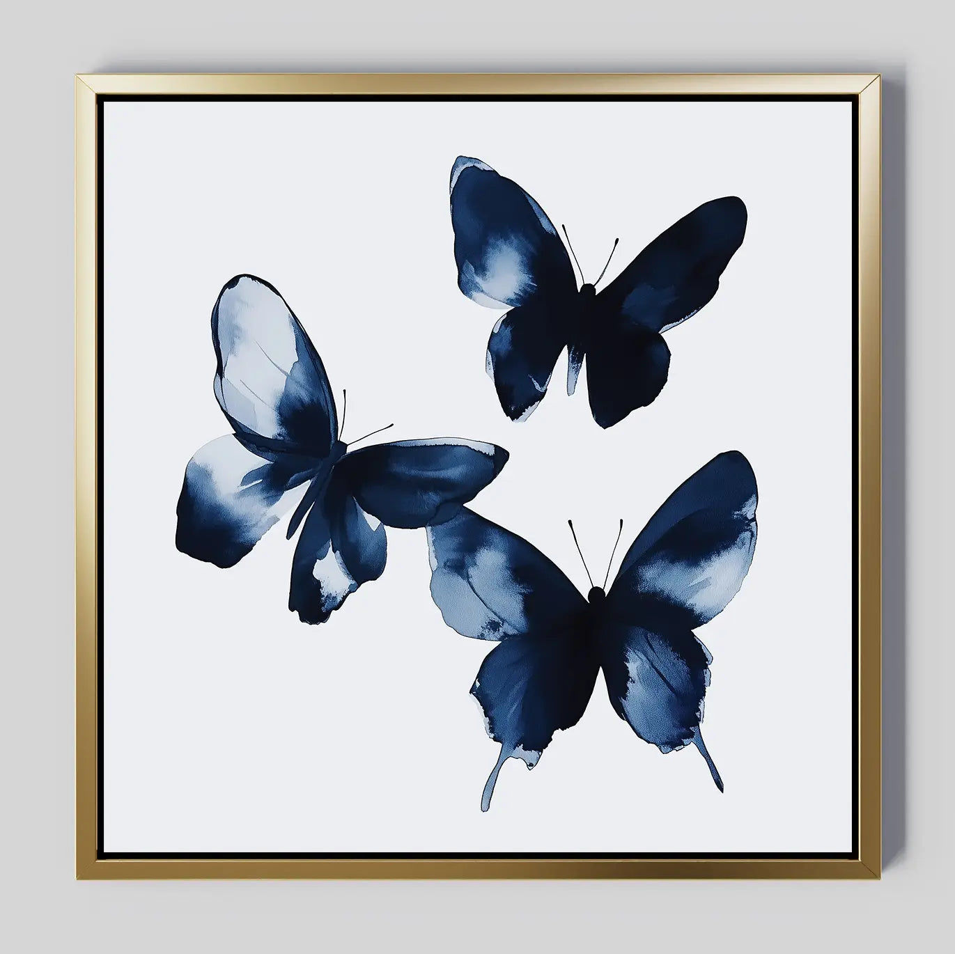 Indigo Flutter Canvas Art: a framed print with three blue abstract butterflies on a white background, finished with a gold metallic frame—ideal for adding modern decor style to your home.