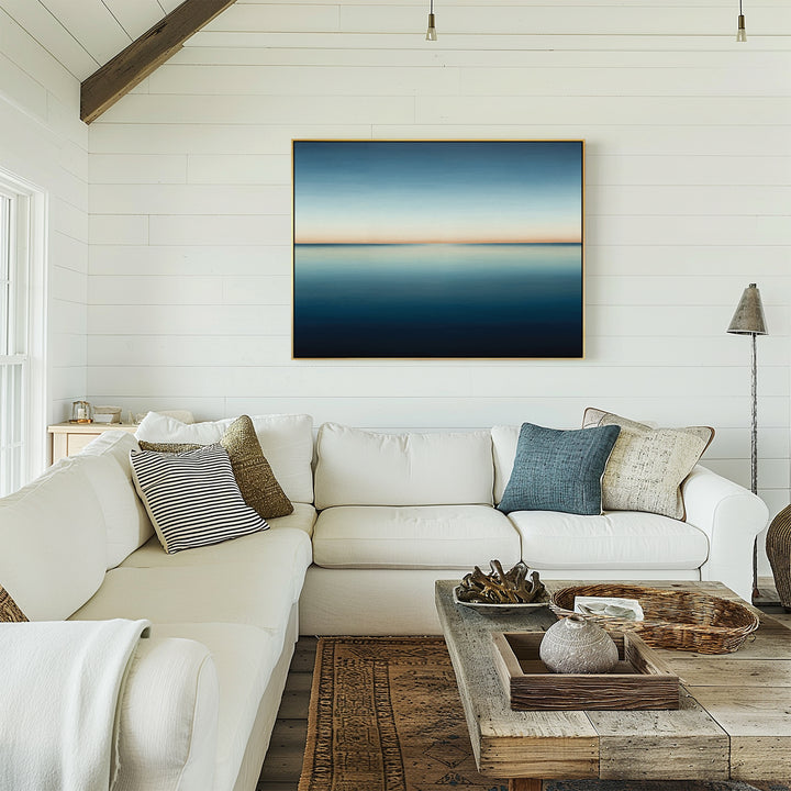 A bright, airy living room with white shiplap walls, a white sectional sofa with assorted pillows, a rustic wooden coffee table, and the Indigo Passage Canvas Art – Horizontal hanging above the sofa as modern decor.