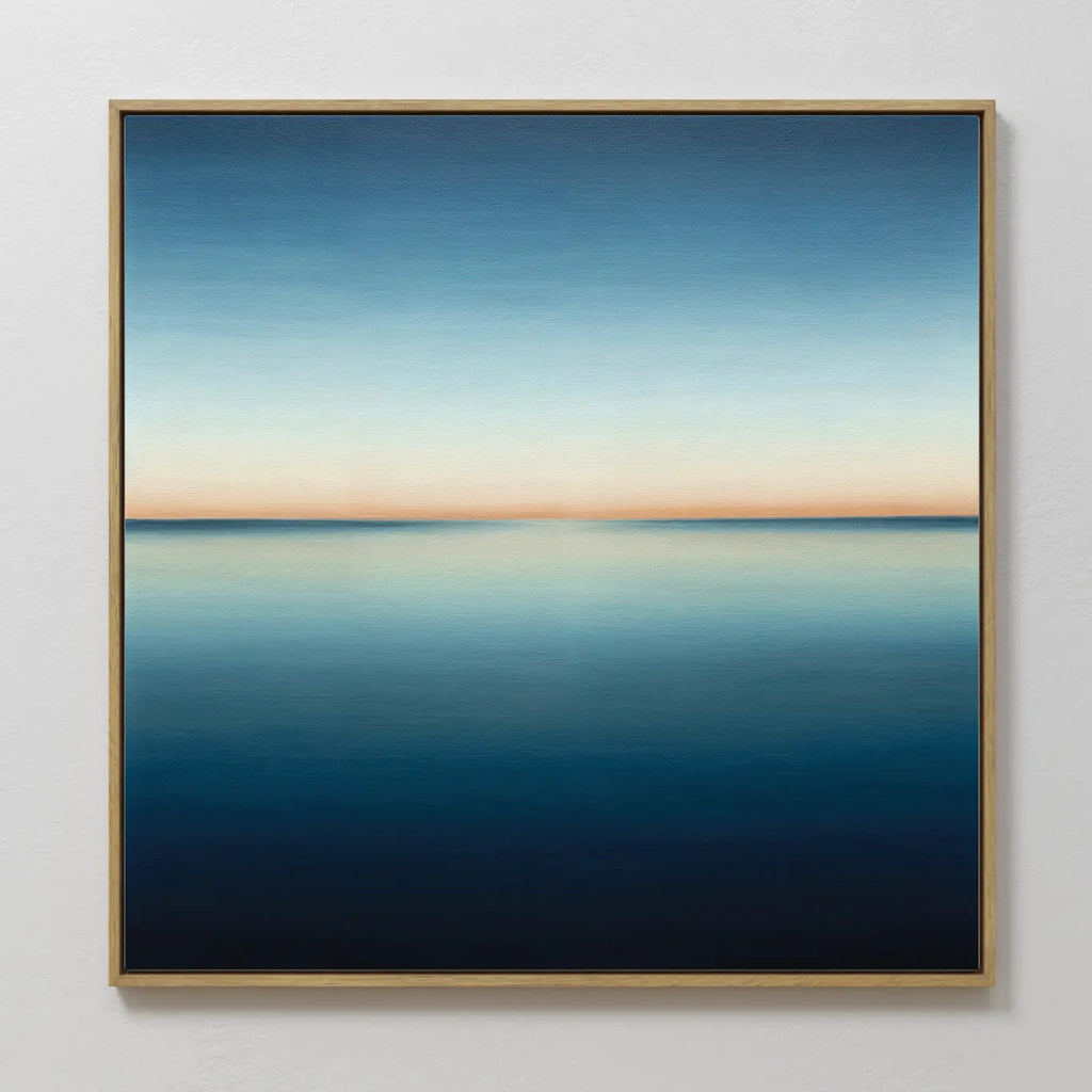 The Indigo Passage Canvas Art is a framed painting of a minimalist seascape, featuring deep blue water and a soft orange horizon—ideal wall art for adding tranquil sunset vibes to modern living room decor.