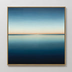 The Indigo Passage Canvas Art is a framed painting of a minimalist seascape, featuring deep blue water and a soft orange horizon—ideal wall art for adding tranquil sunset vibes to modern living room decor.