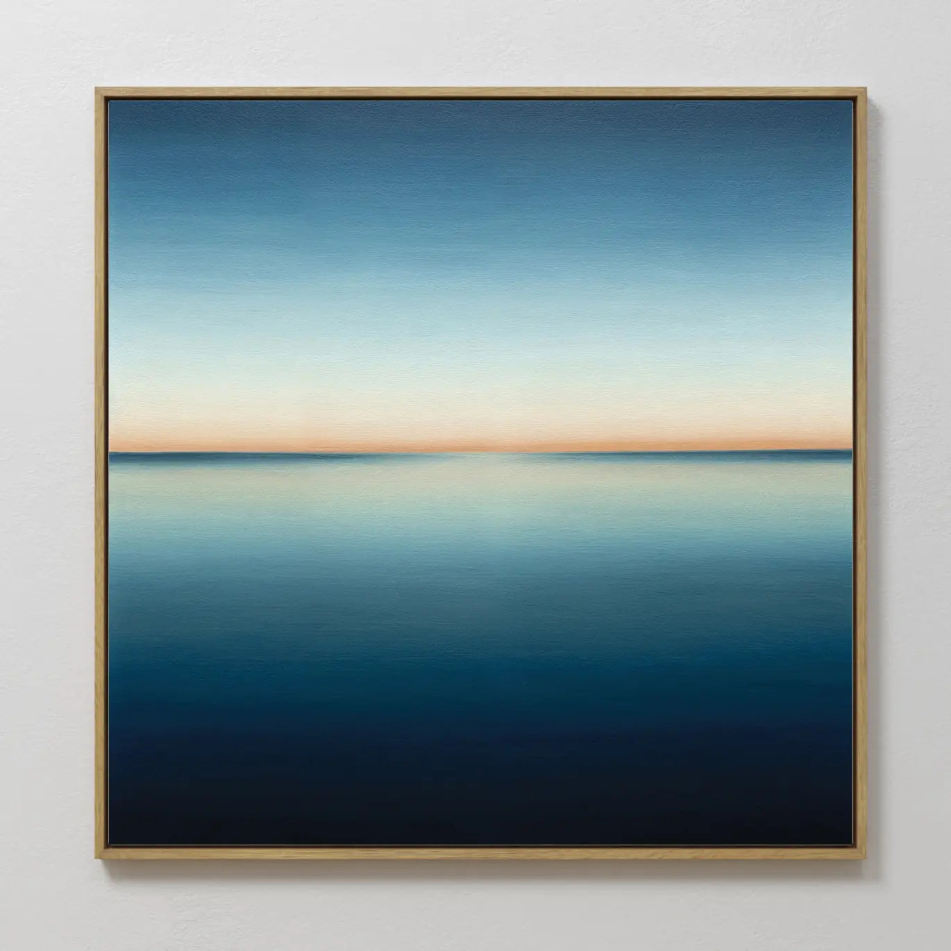 The Indigo Passage Canvas Art is a framed painting of a minimalist seascape, featuring deep blue water and a soft orange horizon—ideal wall art for adding tranquil sunset vibes to modern living room decor.