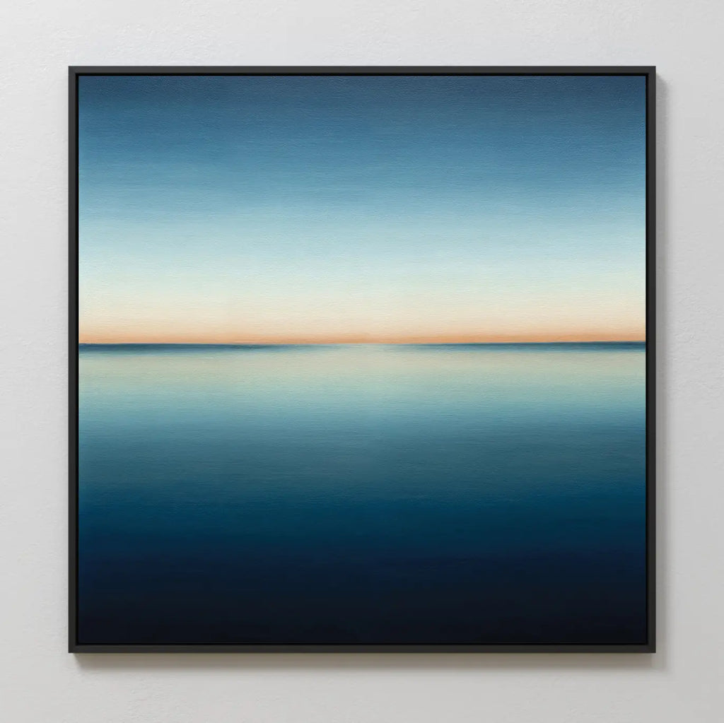 Indigo Passage Canvas Art is a framed painting with a calm, minimal seascape and clear horizon, featuring indigo hues that blend from light blue to peach—perfect minimalist wall art for modern living room decor.