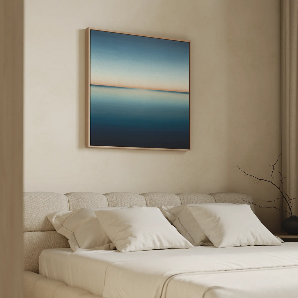 A minimalist bedroom with a beige upholstered bed, white pillows, and the Indigo Passage Canvas Art—a large minimalist piece in blue and beige tones—hanging above the bed.