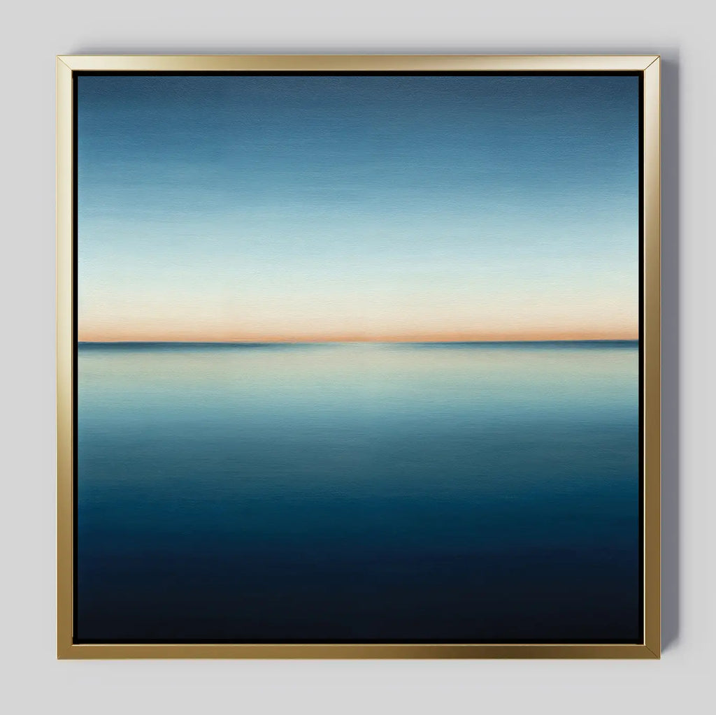 Indigo Passage Canvas Art: A framed painting featuring a serene blue seascape with a soft orange sunset, ideal as indigo wall art for minimalist decor or to enhance modern living rooms.