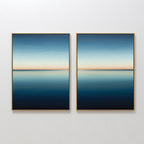 The Indigo Passage Set of 2 features minimalist wall art with framed paintings showing serene seascapes—calm blue water, a gentle horizon, and gradient skies fading from light to deep blue with a soft orange band.