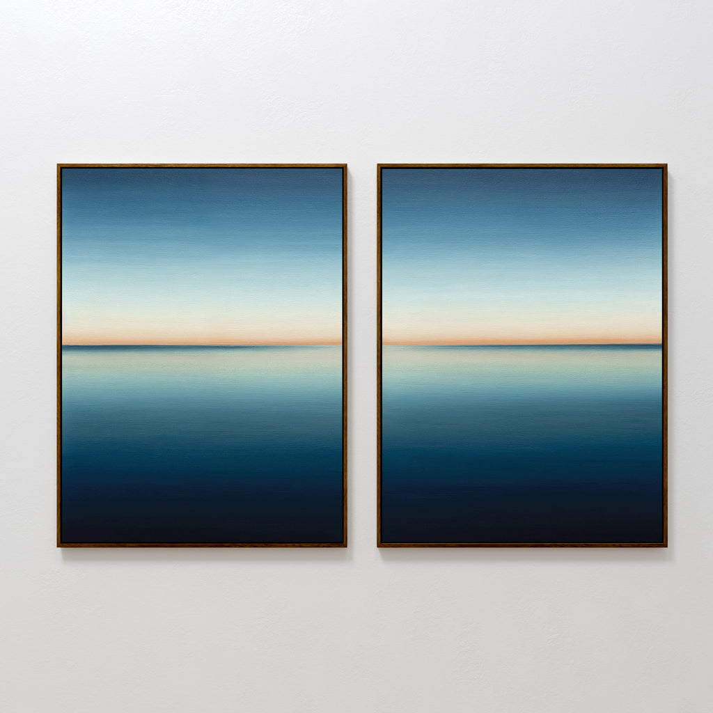 The Indigo Passage Set of 2 features minimalist framed wall art of calm water reflecting the sky in deep blue to peach tones—ideal for adding a tranquil, modern touch to your living room decor.