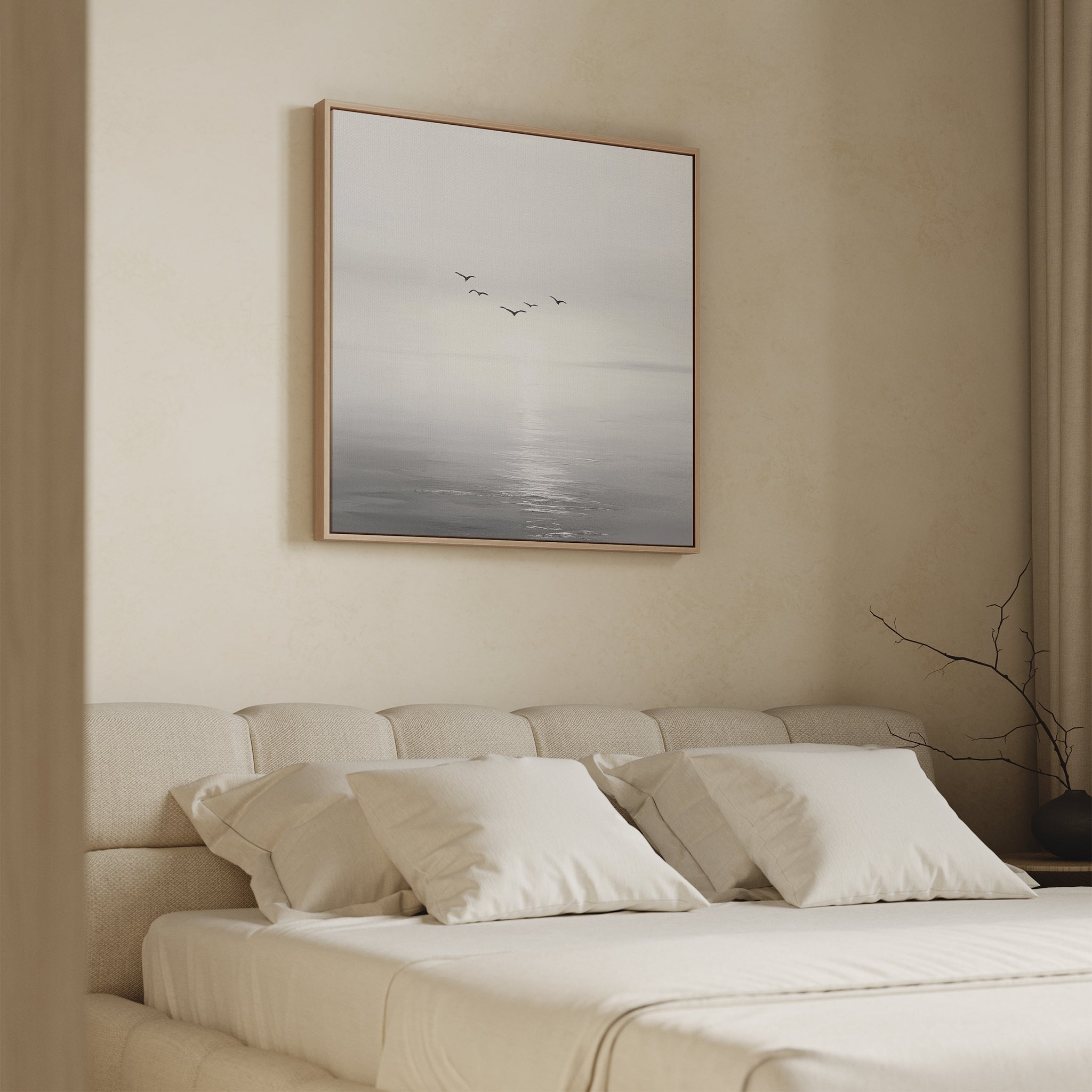 A minimalistic bedroom features the Into the Light Canvas Art above a beige upholstered bed with white pillows. A bare branch in a vase on a nearby table adds to the room’s tranquil, serene feel.