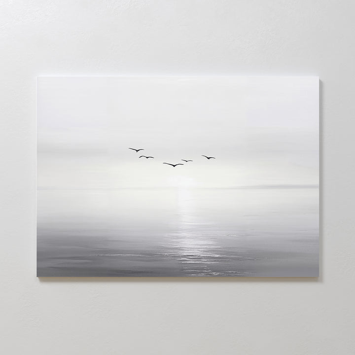 Into the Light Canvas Art – Horizontal features a minimalist, gray-toned seascape with five birds flying above gentle water, ideal as large wall art to create a serene ambiance in your living room on a plain white wall.