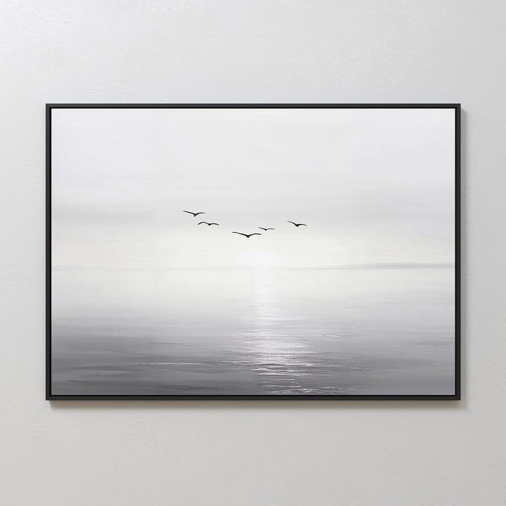 “Into the Light Canvas Art – Horizontal” is a framed minimalist wall art print featuring a black and white seascape with five birds flying above calm water and a soft, hazy horizon—ideal for living room decor.