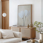 A minimalist living room featuring a light wood sideboard, neutral vases, potted plant, white sofa, and the Ivory Buds Canvas Art. Soft beige and cream decor makes it ideal for lovers of neutral-toned interiors.