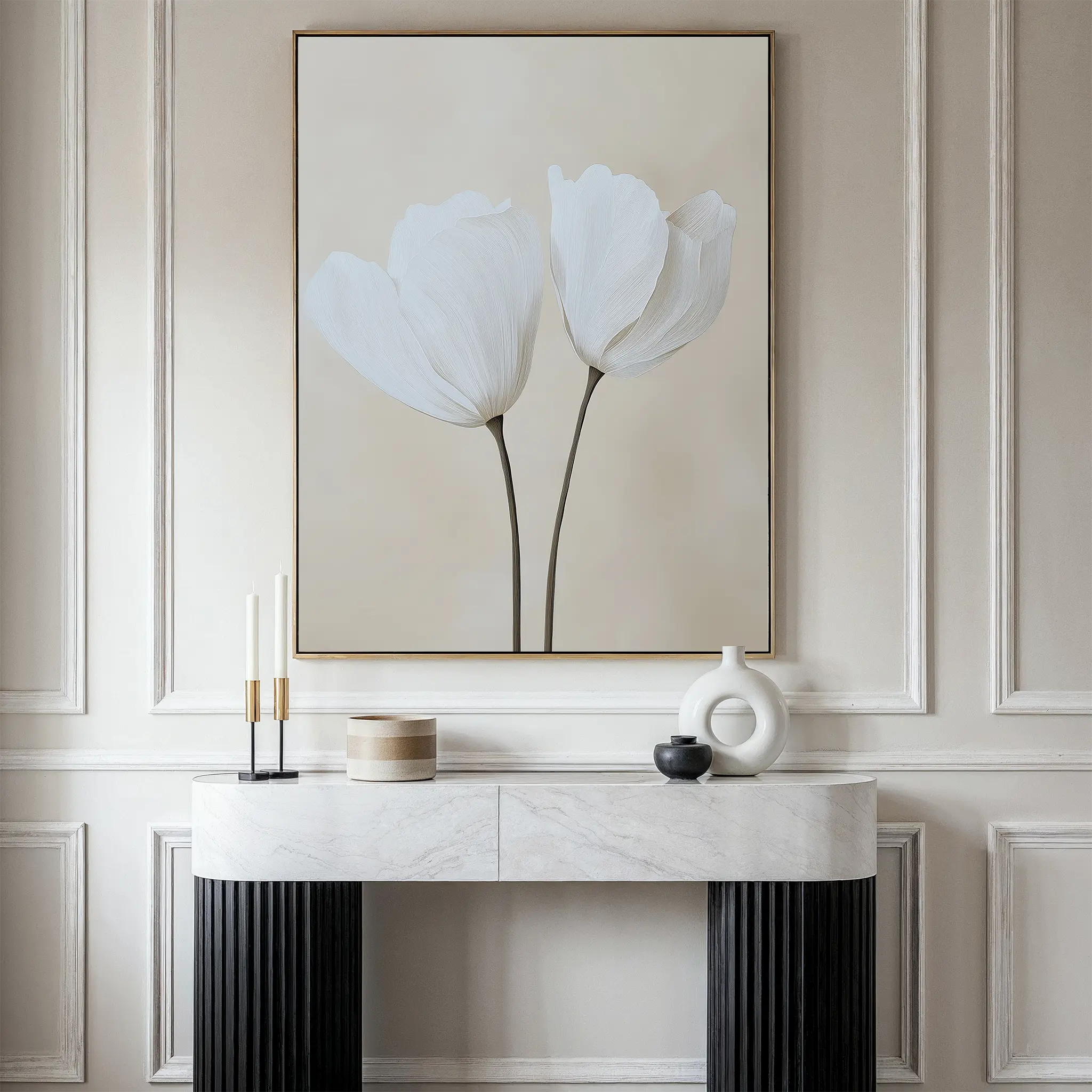 Minimalist decor shines in this neutral-toned interior, featuring a marble console table with vases and candles. Above, the Ivory Buds Canvas Art—a large framed floral artwork—hangs against paneled beige walls.