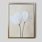 The Ivory Buds Canvas Art features two delicate white flowers with long stems on a light beige background in a slim gold frame—ideal for minimalist or neutral-toned interiors.