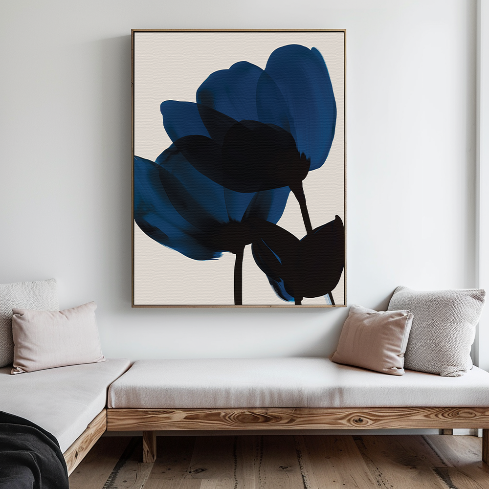 A minimalist living room features a light wooden bench, neutral cushions, and the Bloom Abstract Canvas Art—a large blue and black floral piece—that adds sophistication to the white wall and enhances your living room decor.