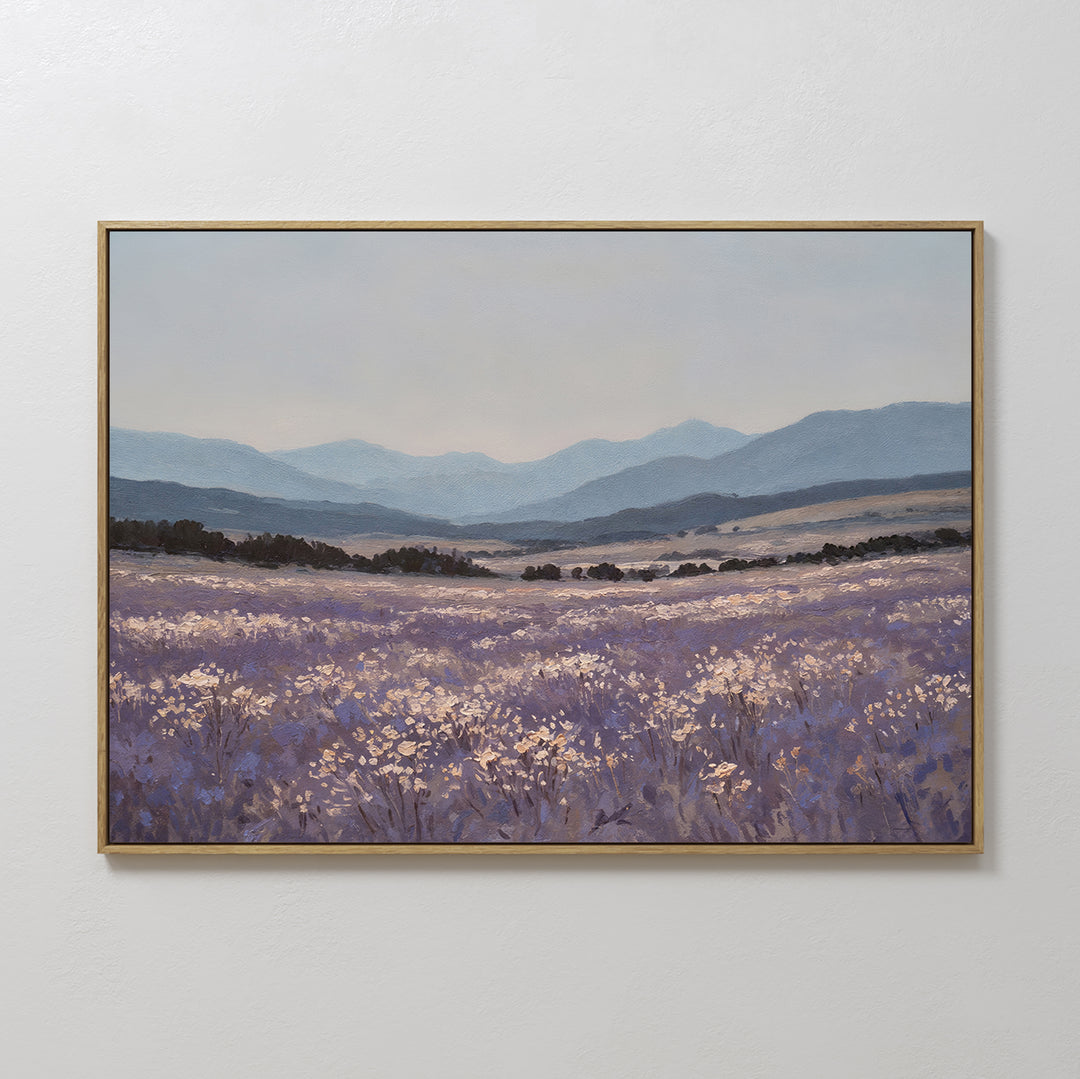 The Lavender Terrain Canvas Art features a calming lavender field with white blooms, rolling hills, and blue mountains beneath a pale sky—perfect for adding serene style to any plain, light-colored wall.