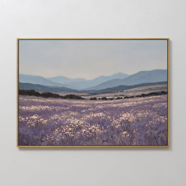 The Lavender Terrain Canvas Art features a calming lavender field with white blooms, rolling hills, and blue mountains beneath a pale sky—perfect for adding serene style to any plain, light-colored wall.