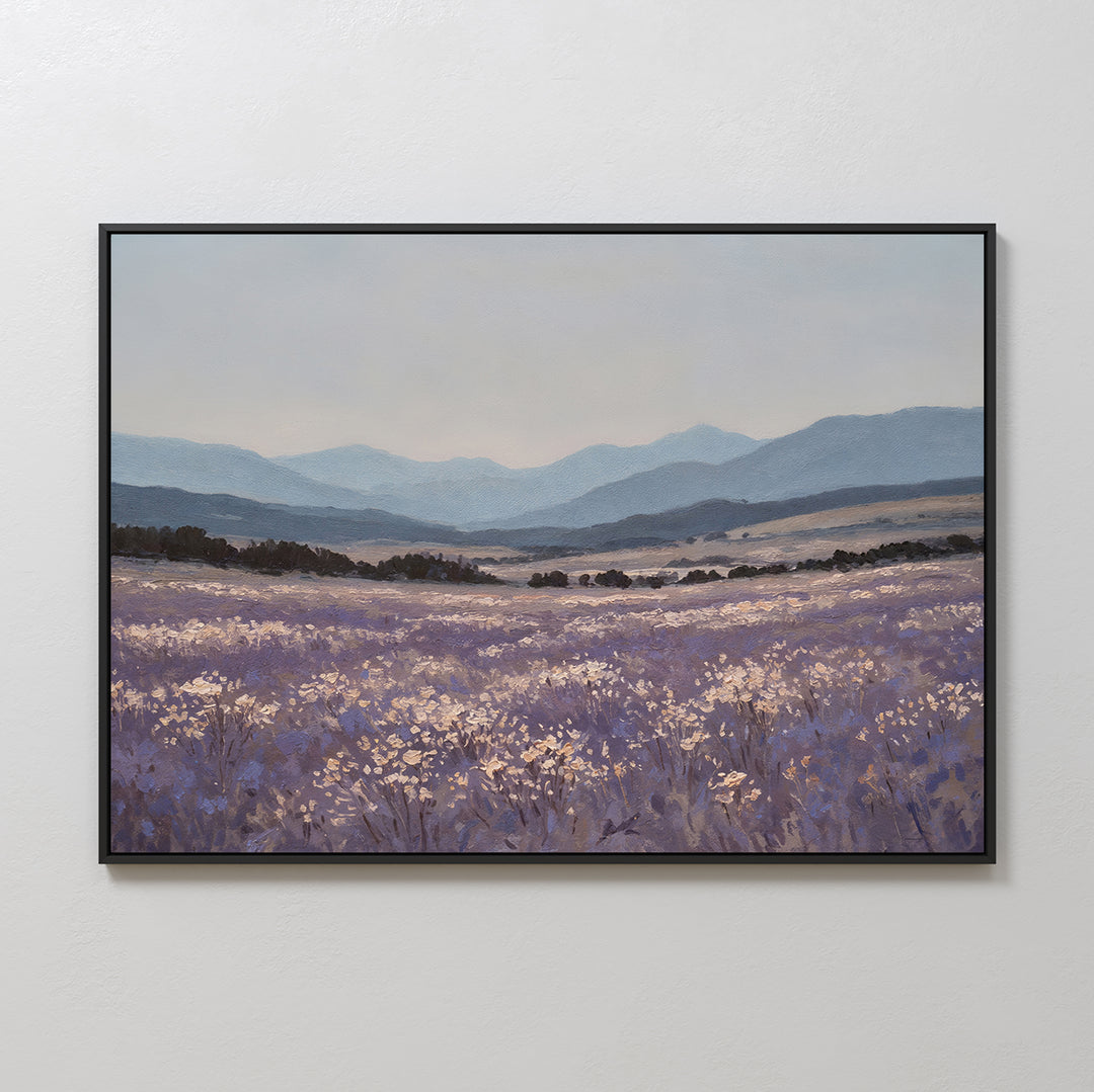 The Lavender Terrain Canvas Art features a serene field of purple wildflowers and white blooms with rolling hills and distant blue mountains under a cloudy sky, bringing minimalist elegance to any plain white wall.
