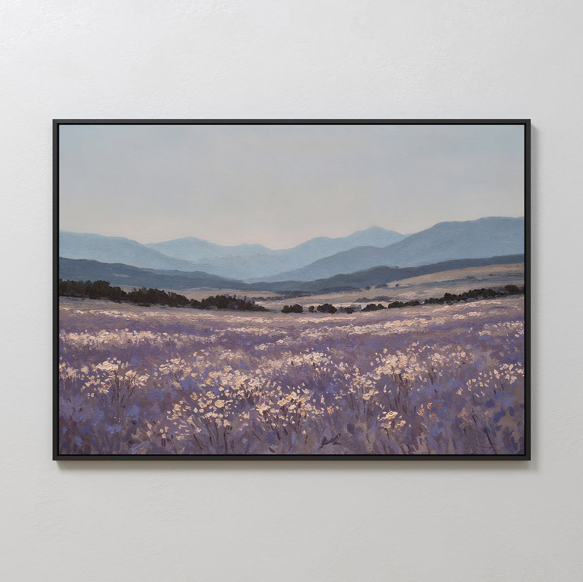 The Lavender Terrain Canvas Art features a serene field of purple wildflowers and white blooms with rolling hills and distant blue mountains under a cloudy sky, bringing minimalist elegance to any plain white wall.