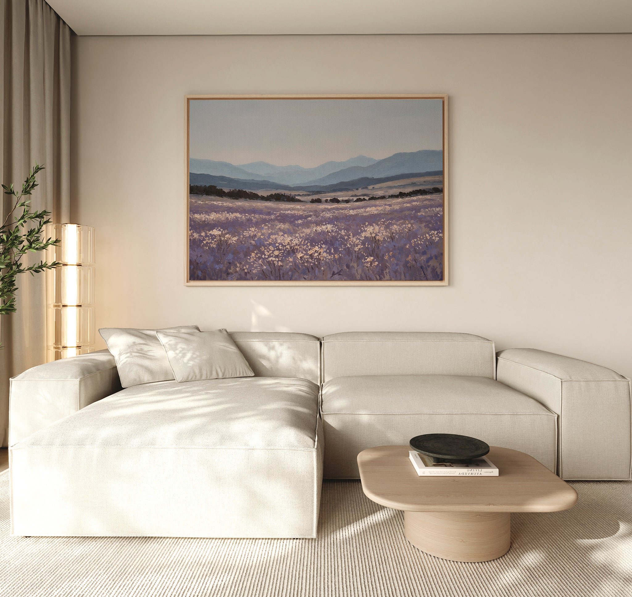 A modern living room with a light beige sectional sofa, wooden coffee table, potted plant, and the Lavender Terrain Canvas Art featuring lavender fields and mountains hanging on a neutral wall. Natural light fills the calming space.