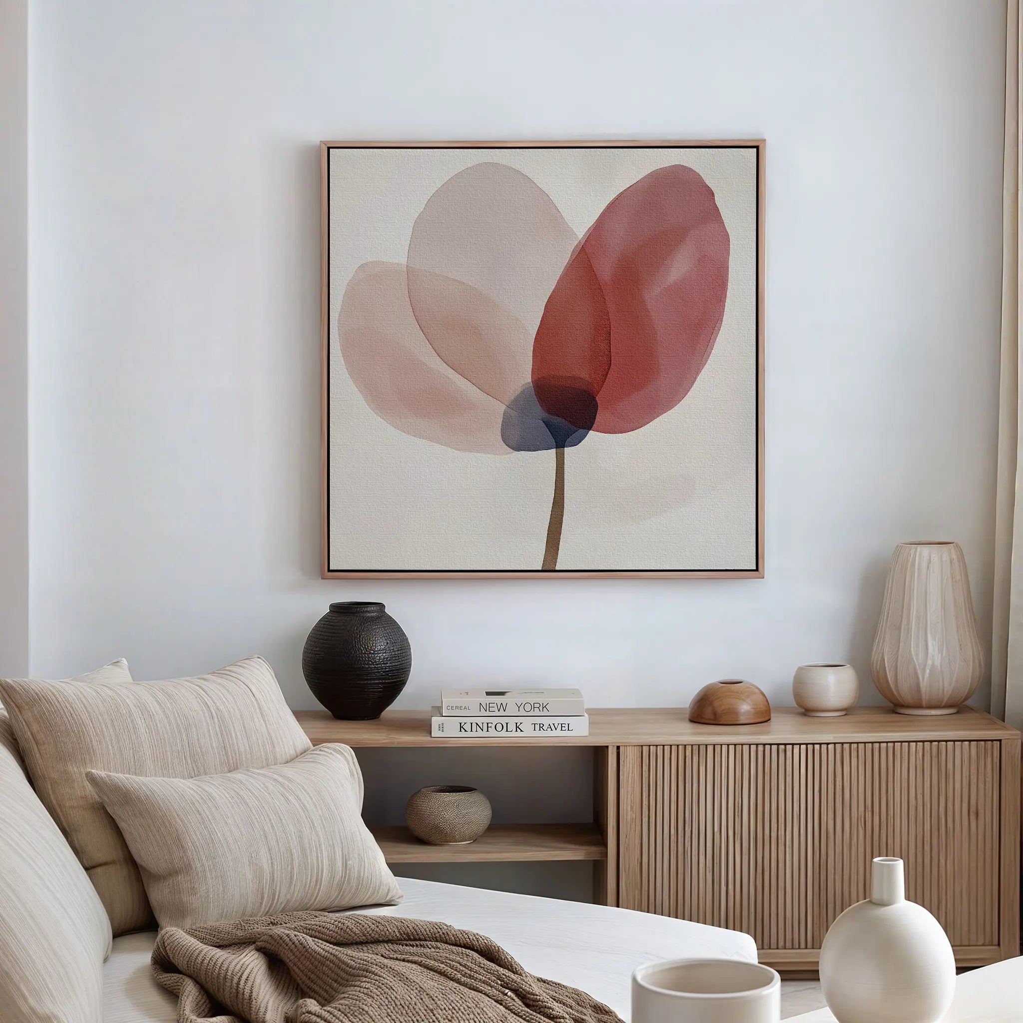 A minimalist living room with a neutral couch, beige cushions, wooden console, and the Layered Bloom Canvas Art—a modern abstract floral featuring soft pink and red petals—adds blush decor above the sofa.