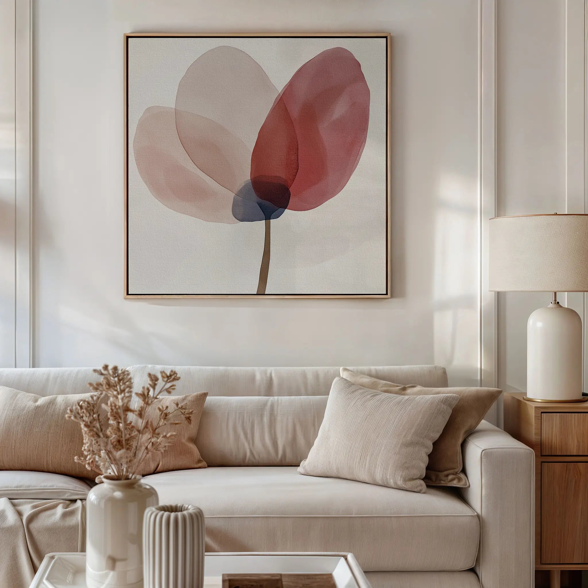 A modern living room with a white sofa, neutral cushions, a wooden side table with a cream lamp, dried flowers in a vase, and the Layered Bloom Canvas Art as floral wall art brings elegance to the space.