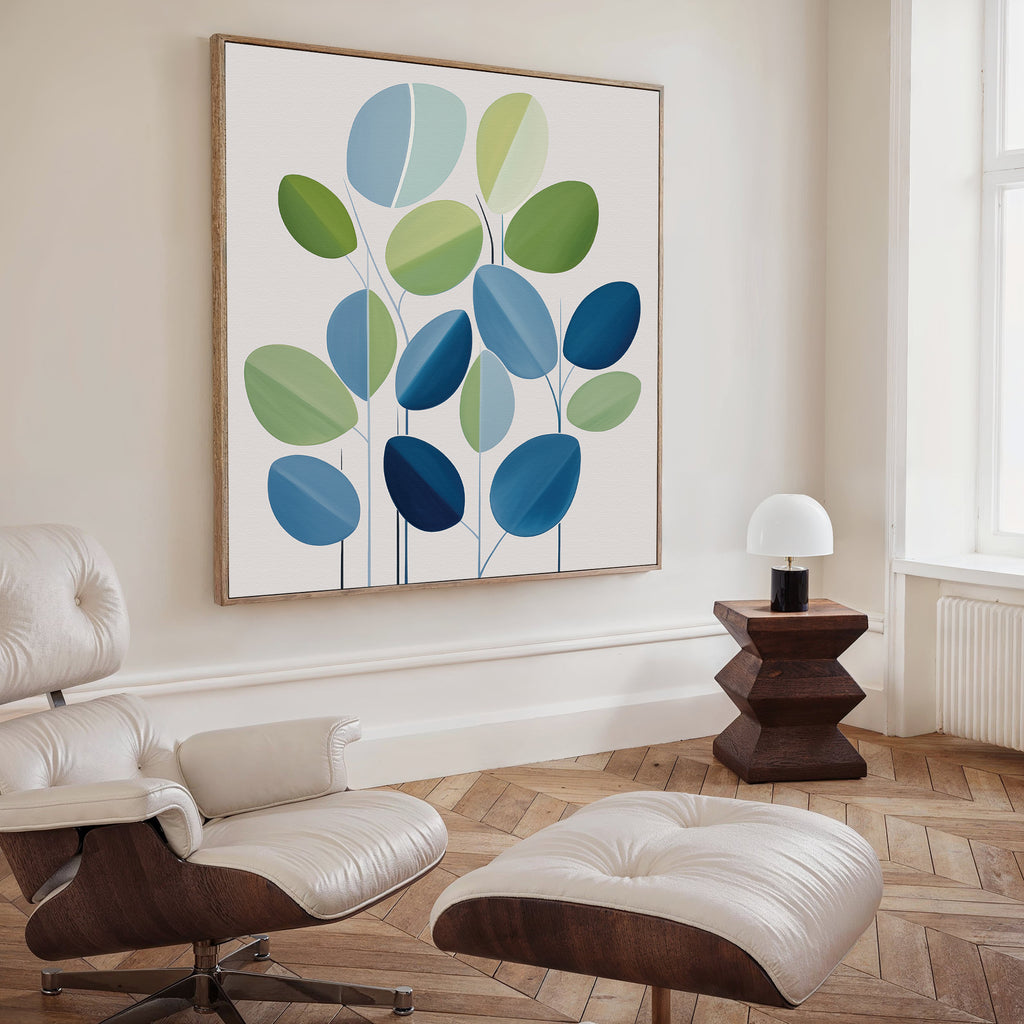 A modern living room with a white lounge chair and ottoman, wooden side table and lamp, and the Layered Stillness Canvas Art featuring blue and green leaf shapes. Light herringbone wood floors and a tall window complete the look.
