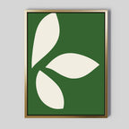 The Leaf Silhouette Abstract Canvas Art features three bold white leaves in a circular design on a dark green background, set in a metallic gold frame—ideal minimalist wall art to add modern elegance to any living room decor.