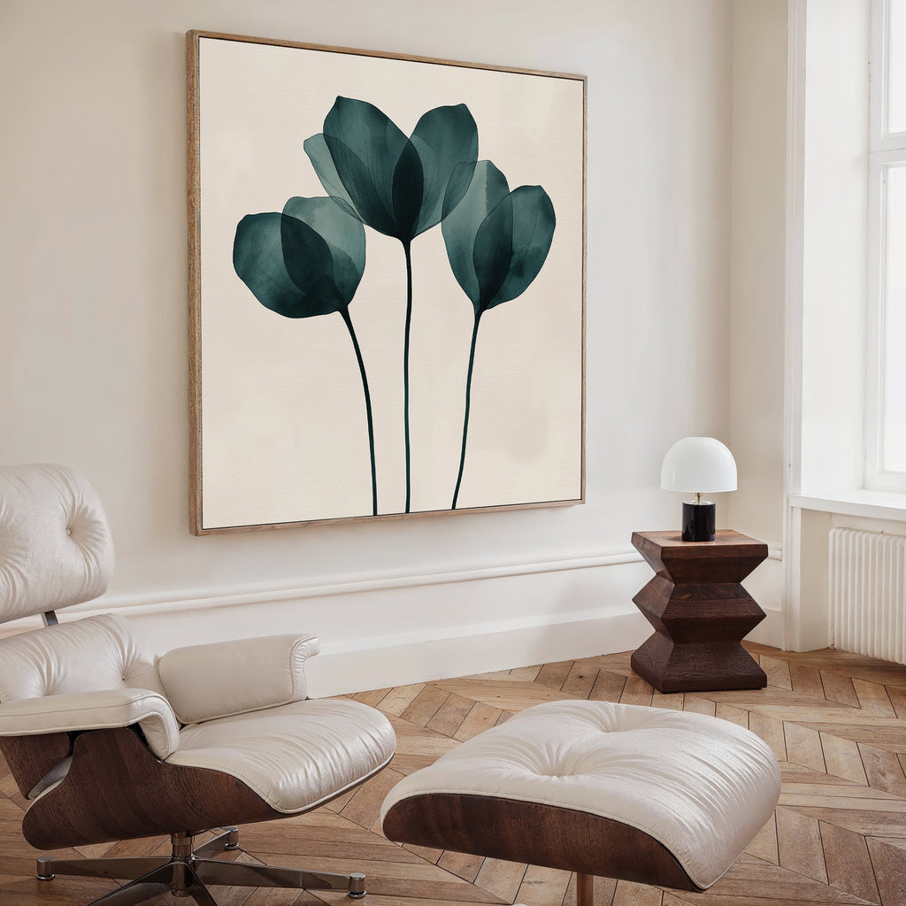 A modern living room with a white lounge chair and ottoman, wooden side table with white lamp, and Leafy Balance Canvas Art featuring three dark green abstract flowers on the wall.