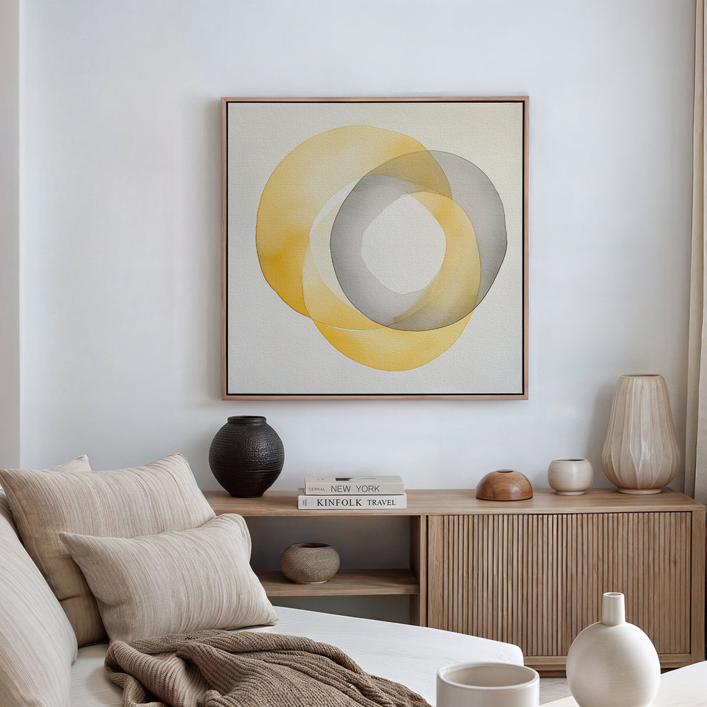 A modern, minimalist living room with a beige sofa, neutral cushions, a wooden sideboard, ceramic vases, stacked books, and the Lemon Light Canvas Art featuring abstract yellow and gray design displayed on a white wall.