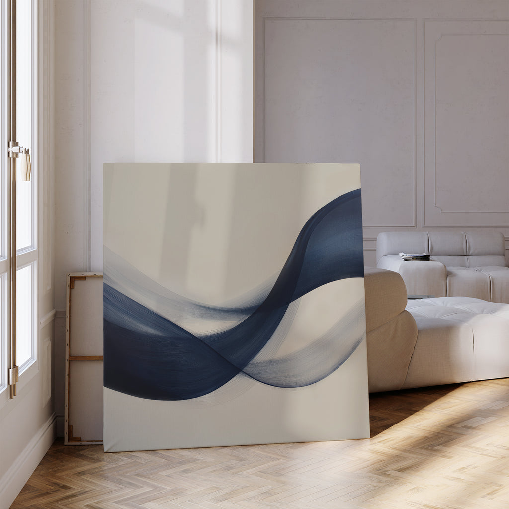 The Tidal Flow Canvas Art, featuring flowing blue wave brushstrokes, leans against the wall of a bright modern living room with parquet floors and a beige sofa—ideal minimalist decor for stylish spaces. Sunlight pours through tall windows.
