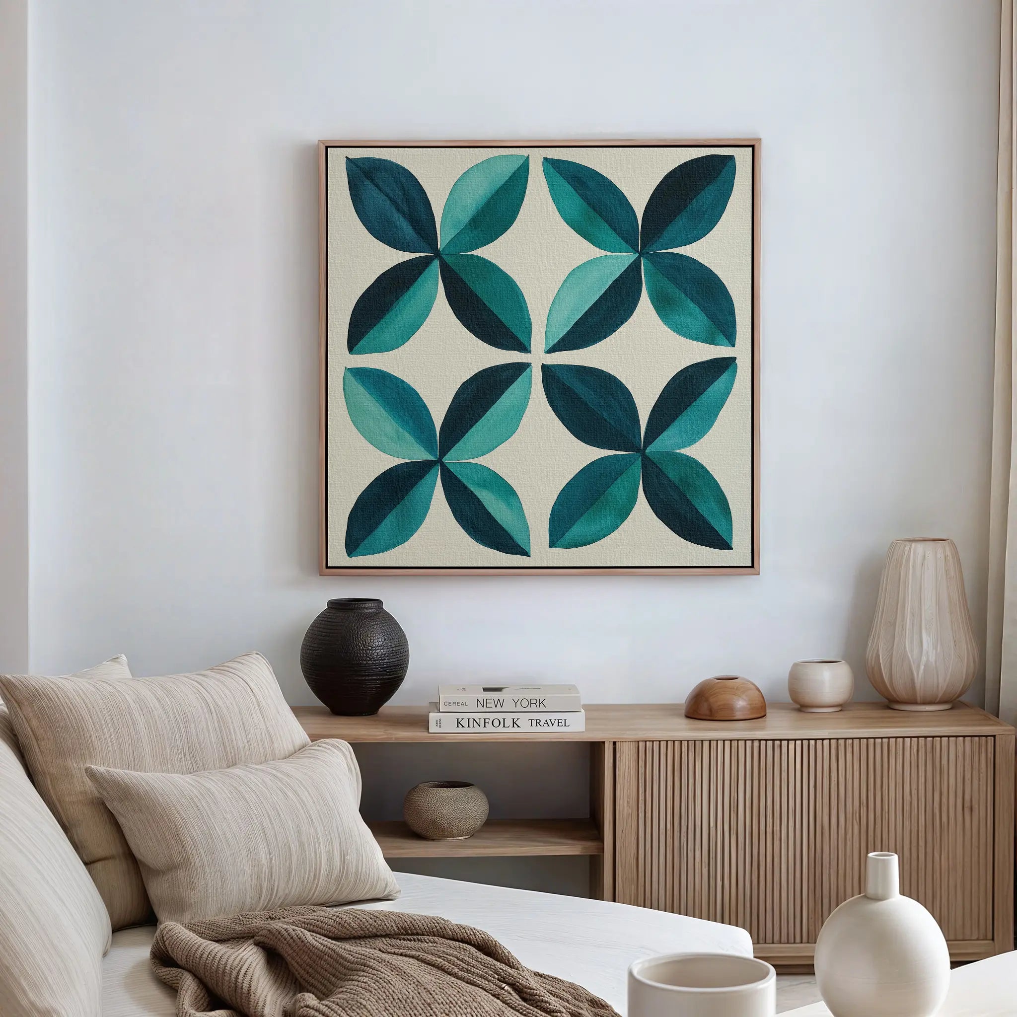 A modern living room with a beige couch, neutral cushions, wood sideboard, and minimalist decor features the Marine Mosaic Canvas Art—an abstract blue and teal petal design—hanging above the sideboard on the white wall.