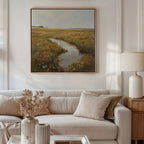 A cozy living room features a beige sofa, neutral pillows, and a table with dried flower vases. The Marshland Stream Canvas Art hangs above the sofa, depicting a grassy field and stream for serene, inviting decor.