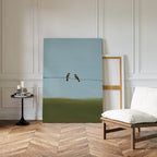 A minimalist room with chevron wood flooring, a cushioned chair, and a round black side table. Meadow Line Canvas Art rests against the white paneled wall, bringing subtle elegance to the space.