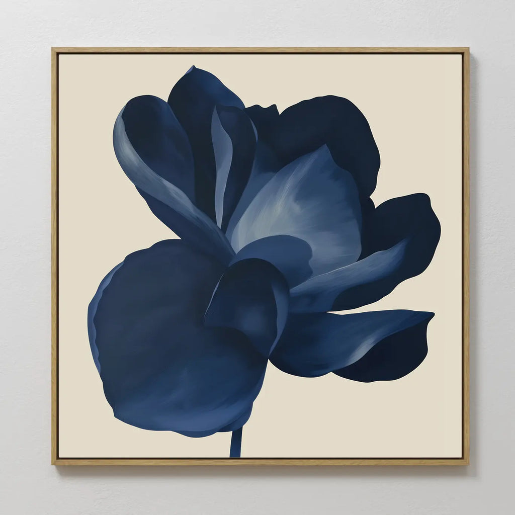 The Midnight Bloom Canvas Art – Square features a large, dark blue flower with soft shading on a light beige background, set in a simple wooden frame—ideal wall art for modern spaces.