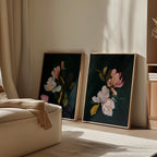 The Midnight Blossoms Set of 2 framed floral paintings leans against a light wall in a cozy room, with sunlight casting shadows across the art, beige sofa, and wooden furniture for an inviting home decor vibe.