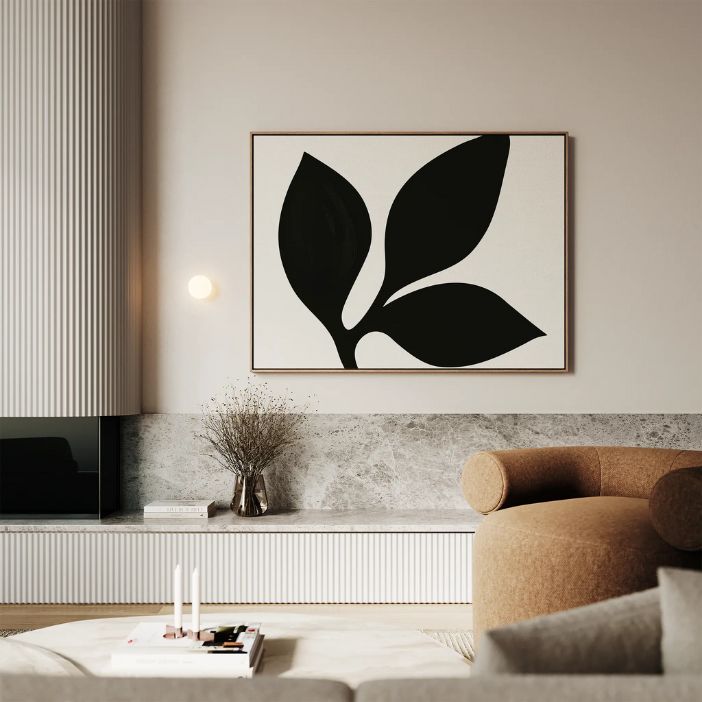 A modern living room features the Midnight Botanist Canvas Art above a brown curved sofa, complemented by a minimalist light fixture, dried flowers in a vase, and a marble-topped low shelf—perfect for stylish decor.