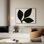 A modern living room features the Midnight Botanist Canvas Art above a brown curved sofa, complemented by a minimalist light fixture, dried flowers in a vase, and a marble-topped low shelf—perfect for stylish decor.