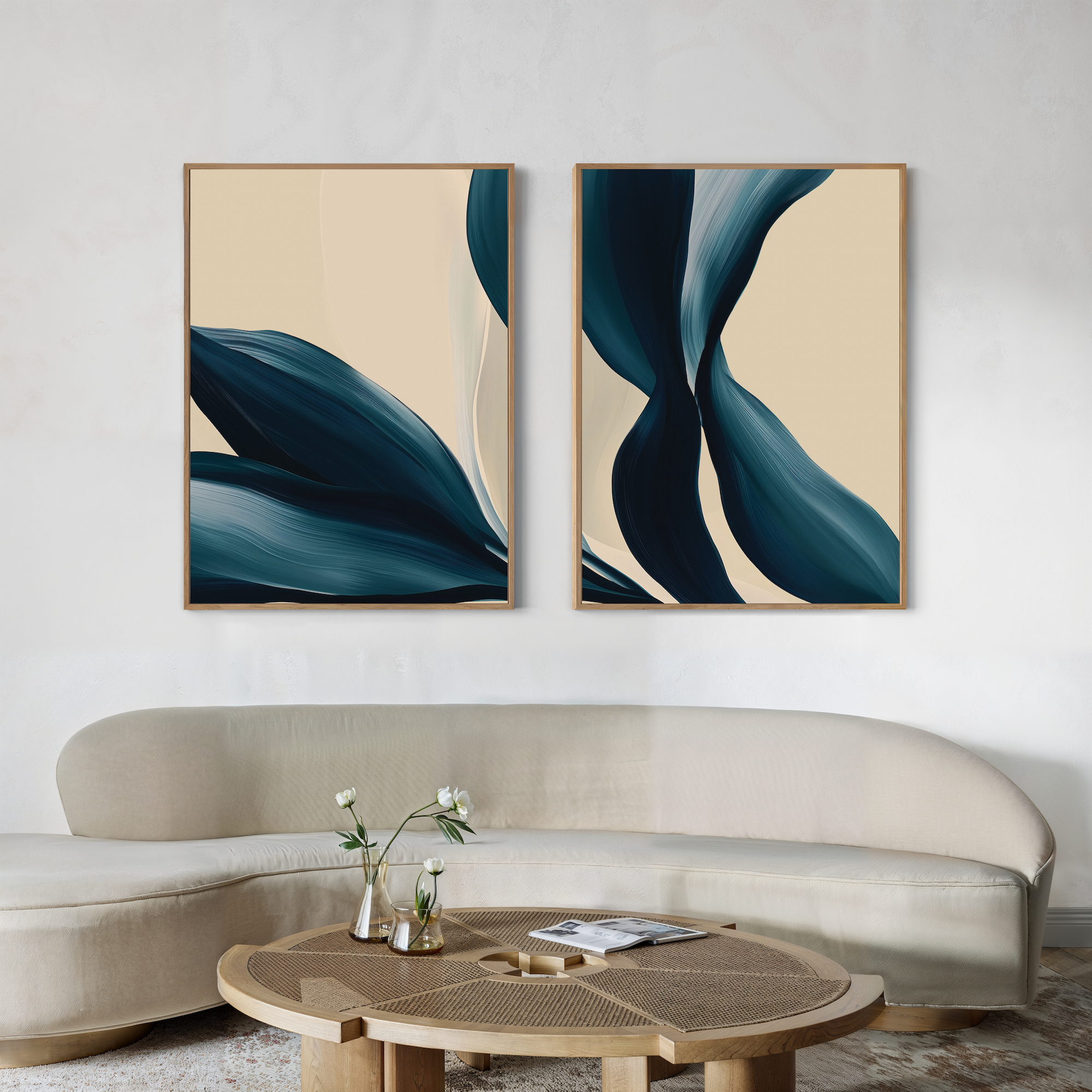 A modern living room features a curved beige sofa, a round wooden coffee table with white flowers in a vase, and two large Midnight Foliage Set of 2 abstract blue and cream artworks on the wall.